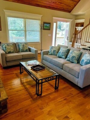 A living room with two sofas, a coffee table, and a staircase.