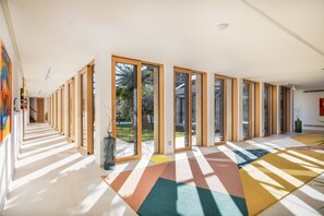 A spacious hallway with large windows, a colorful geometric carpet, and a view of the outdoors.