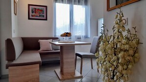 Un salon moderne avec un canapé, une petite table à manger et une plante décorative.
