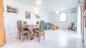 Un coin repas avec une table dressée pour quatre personnes, un canapé et un téléviseur dans le salon.