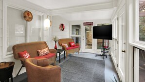 A cozy living room with wicker furniture, a flat-screen TV, and a large window. - Hoosier Haven Spacious Retreat (Bloomington)