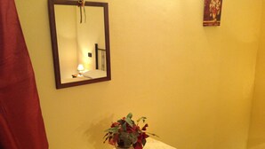 A bathroom with a mirror, a vase of flowers, a tissue box, and a towel on a small table. - Apartment With one Bedroom, Kitchen, Bathroom Garden and Shared Pool (Chianni)