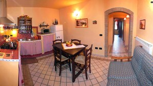A compact kitchen with a dining area, a small refrigerator, and a microwave. - Apartment With one Bedroom, Kitchen, Bathroom Garden and Shared Pool (Chianni)