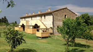 A stone building with a staircase leading to a wooden deck. - Apartment With one Bedroom, Kitchen, Bathroom Garden and Shared Pool (Chianni)