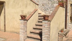A set of stone steps leading to a door, with potted plants on the steps and a stone wall in the background. - Apartment With one Bedroom, Kitchen, Bathroom Garden and Shared Pool (Chianni)