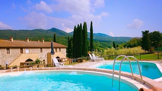 A swimming pool with lounge chairs and a stone building in the background. - Apartment With one Bedroom, Kitchen, Bathroom Garden and Shared Pool (Chianni)