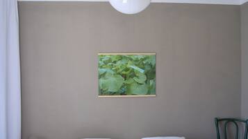 Een slaapkamer met een bed, nachtkastje, lamp en een lijst aan de muur.