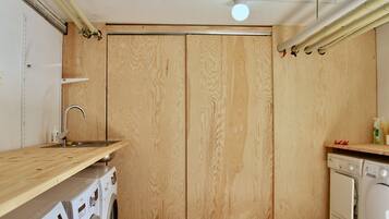 A compact kitchen with wooden cabinets, a built-in washing machine, and a sink.