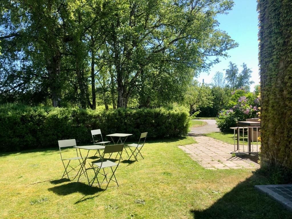Un giardino con tavolo e sedie, un vialetto in pietra e un albero.