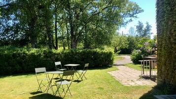 Un giardino con tavolo e sedie, un vialetto in pietra e un albero.