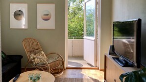 A living room with a sofa, a wicker chair, a coffee table with glasses, a TV, and two framed pictures on the wall. - HEMMET - Simrishamns vandrarhem och B&B (Simrishamn)