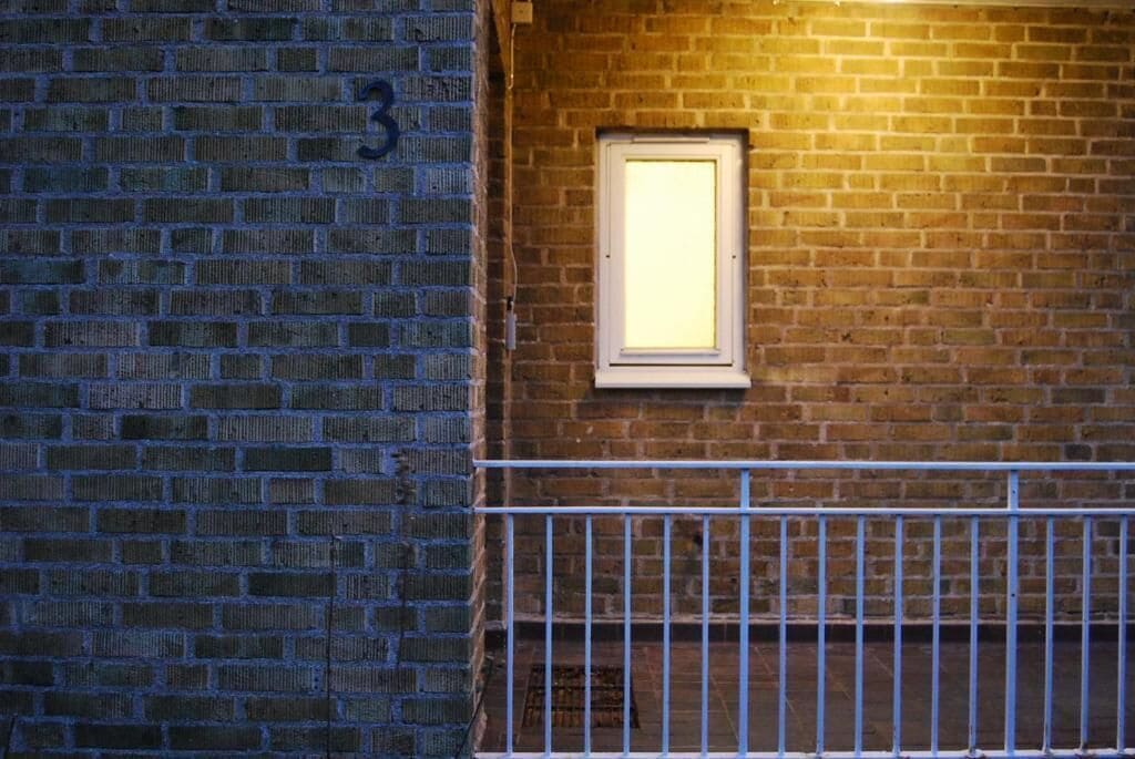 A brick wall with a window and a metal railing.