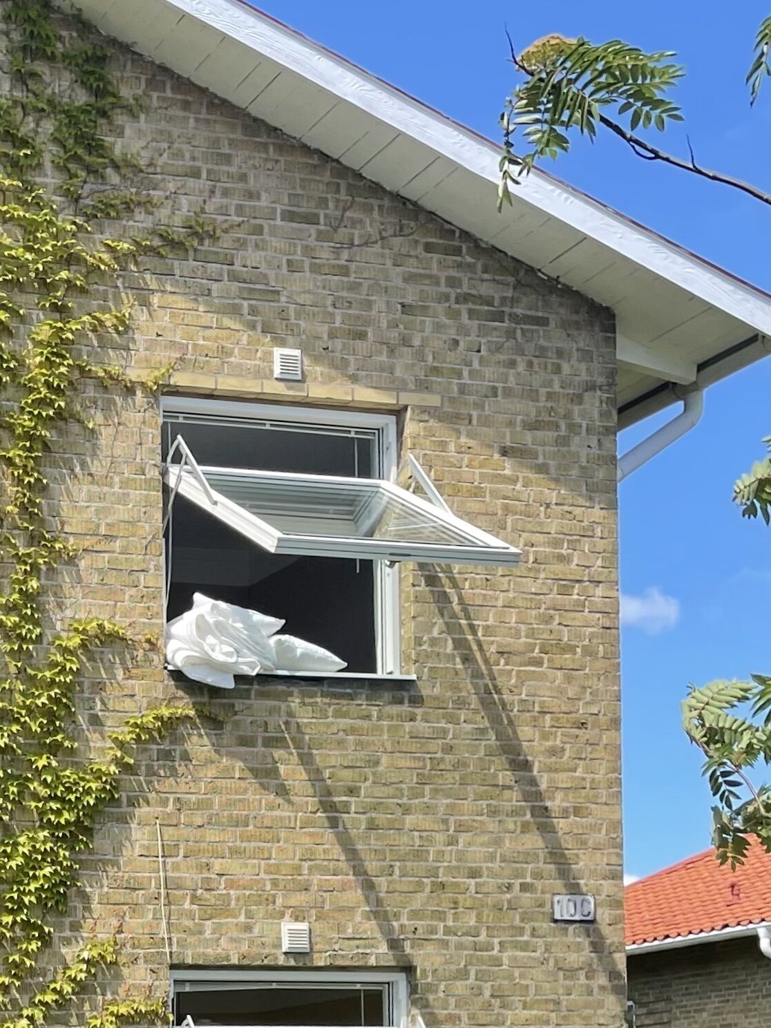 A brick building with a window that has an open awning.