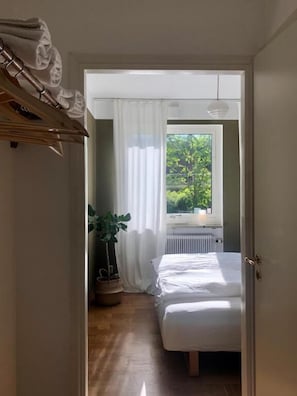 Un dormitorio con cama, una ventana con cortinas, un radiador y una planta en maceta.