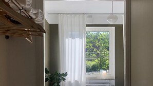 A bedroom with a bed, a window with curtains, a radiator, and a potted plant. - HEMMET - Simrishamns vandrarhem och B&B (Simrishamn)
