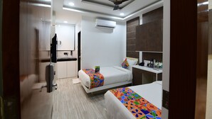 Une chambre d’hôtel moderne équipée de deux lits, d’un ventilateur de plafond, d’un climatiseur, d’un petit bureau et d’un miroir.