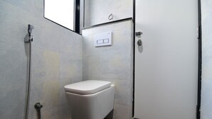 Une petite salle de bain compacte, équipée de toilettes, d’une douche et d’une porte.