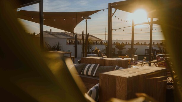 An outdoor seating area with wooden furniture and string lights. - UXCO Kabane Montpellier (Lattes)