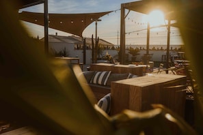 An outdoor seating area with wooden furniture and string lights. - UXCO Kabane Montpellier (Lattes)