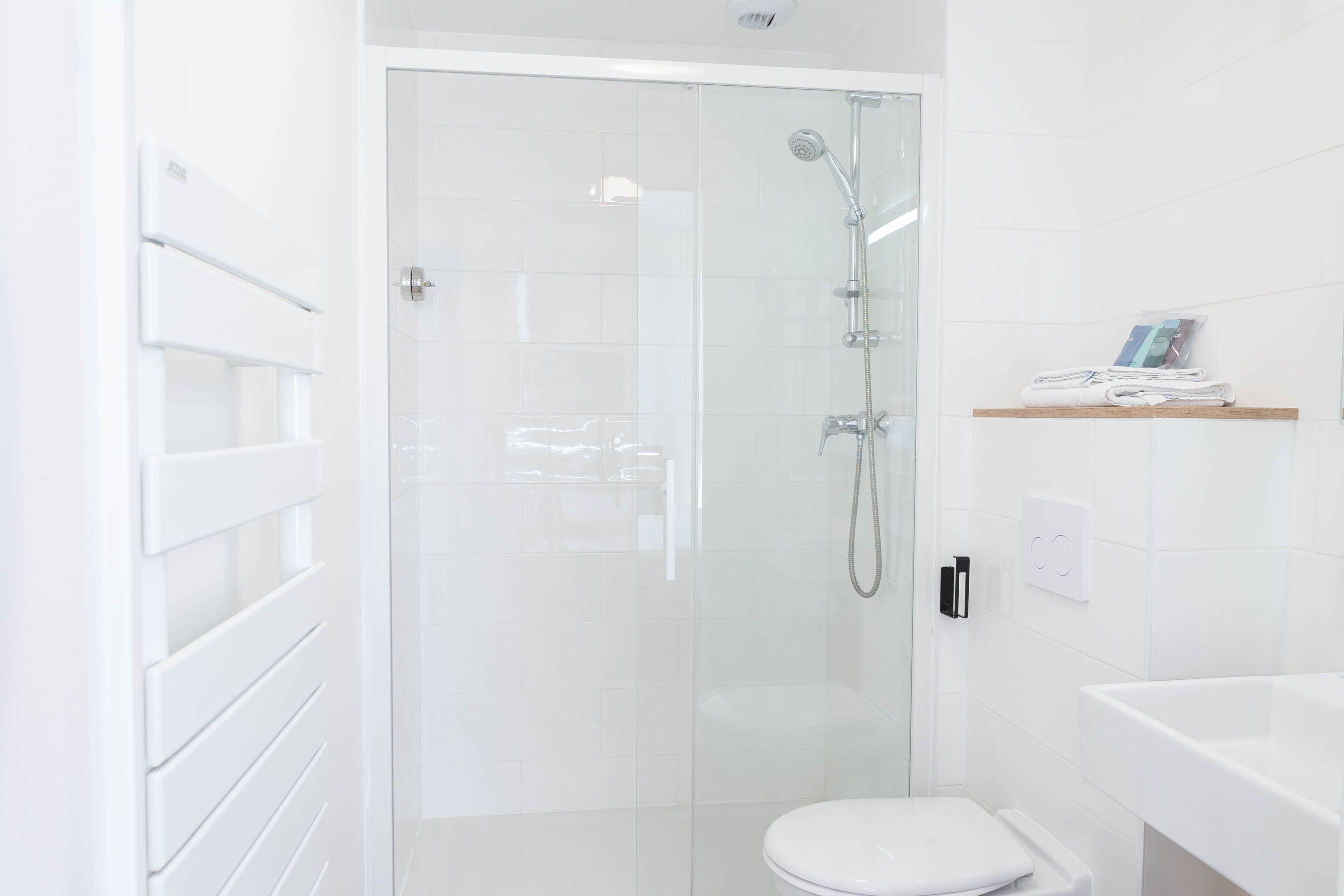 Une salle de bain moderne avec une douche à parois de verre, des toilettes blanches et un lavabo blanc.