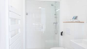Une salle de bain moderne avec une douche à parois de verre, des toilettes blanches et un lavabo blanc.