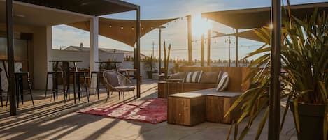Un espace patio extérieur avec un canapé en bois, des chaises et un tapis rouge.