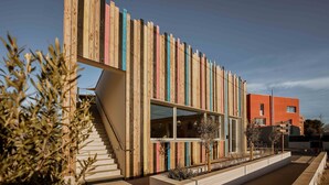 A modern building with a wooden facade, a staircase, and a pathway with planters. - UXCO Kabane Montpellier (Lattes)