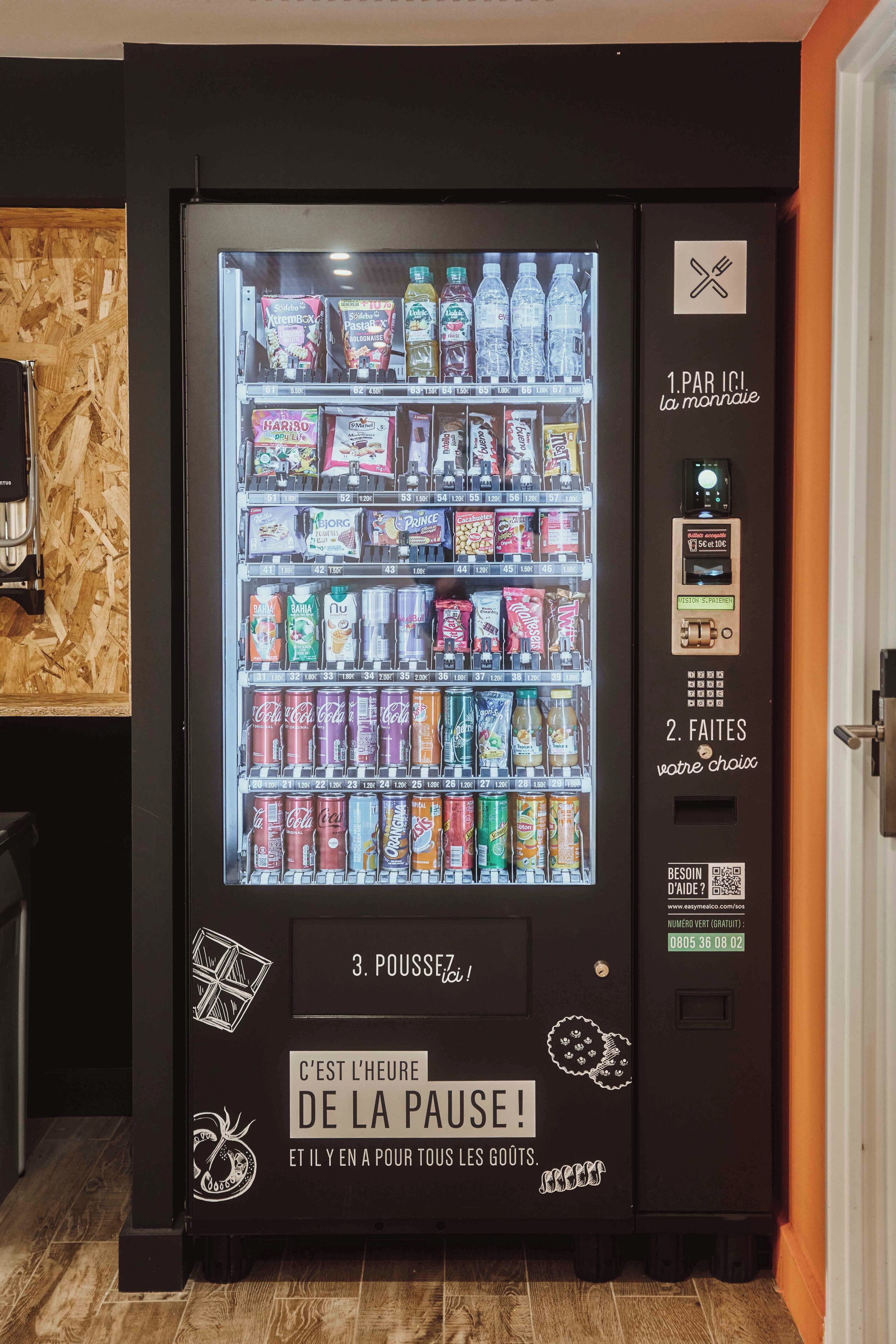 A vending machine with various beverages and snacks, a payment interface, and a sign encouraging to take a break.
