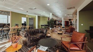 A spacious lounge area with leather sofas, a round table, and a variety of seating options. - UXCO Kabane Montpellier (Lattes)