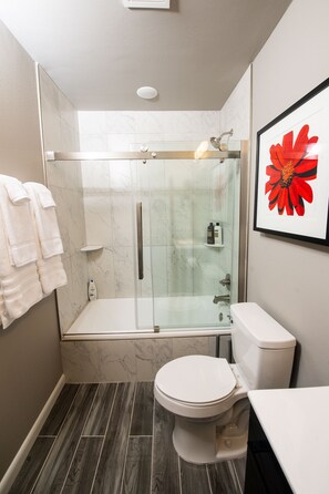 Une salle de bain moderne avec une douche à parois de verre, des toilettes blanches et un sol carrelé en marbre.