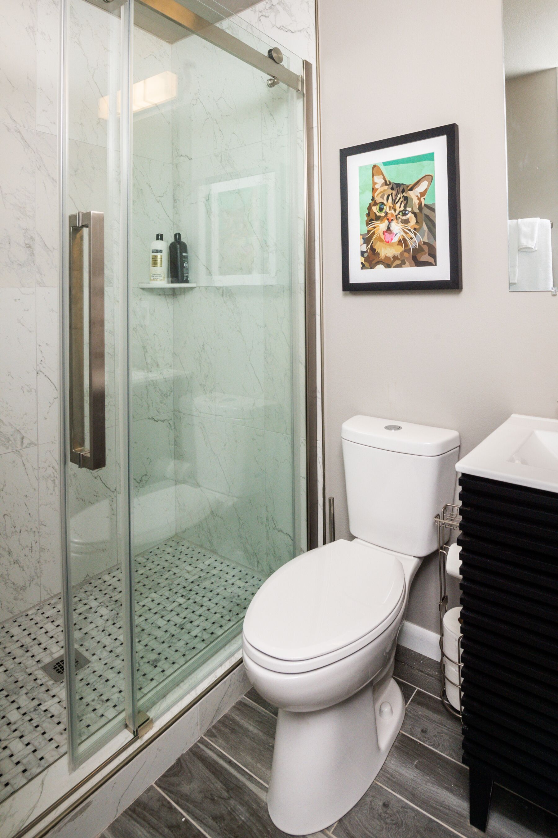 Un baño moderno con cabina de ducha de vidrio, inodoro blanco y tocador negro.