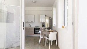 A modern kitchen with white cabinets, a stainless steel refrigerator, and a dining area with a table and chairs. - Trullo Chiara con piscina by Wonderful Italy (Ostuni)
