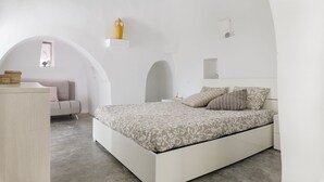 A modern bedroom with a large bed, a small desk, and a chair. There is a window with a view of the sky. - Trullo Chiara con piscina by Wonderful Italy (Ostuni)