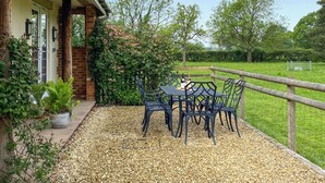 Een terras met een tafel en stoelen, een bakstenen muur en een houten omheining.