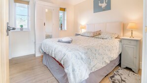 Een slaapkamer met een bed, nachtkastjes, een lampje en een raam met uitzicht.