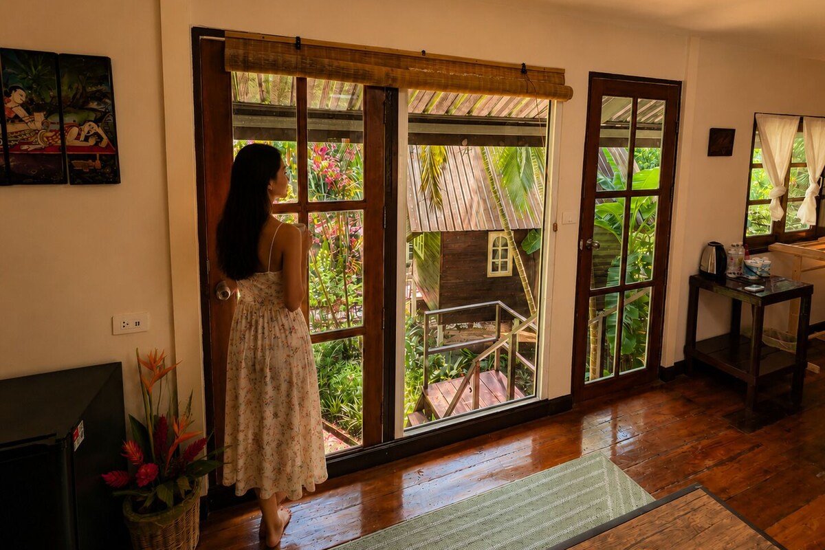 Une pièce avec un plancher en bois, une grande porte-fenêtre coulissante, une petite structure en bois à l’extérieur et un téléviseur sur le côté gauche.