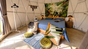 A tented room with a bed, two lamps, a hanging light, and a tapestry. - Vanara Bungalows  (Ko Chang)