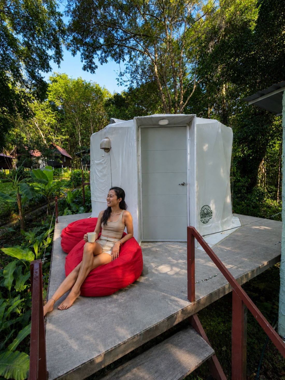 A person sitting on a red bean bag chair in front of a white portable toilet.