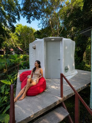 A person sitting on a red bean bag chair in front of a white portable toilet. - Vanara Bungalows  (Ko Chang)