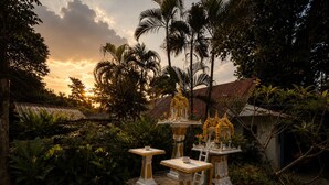 A courtyard with a traditional structure, surrounded by lush greenery and a sunset sky. - Vanara Bungalows  (Ko Chang)