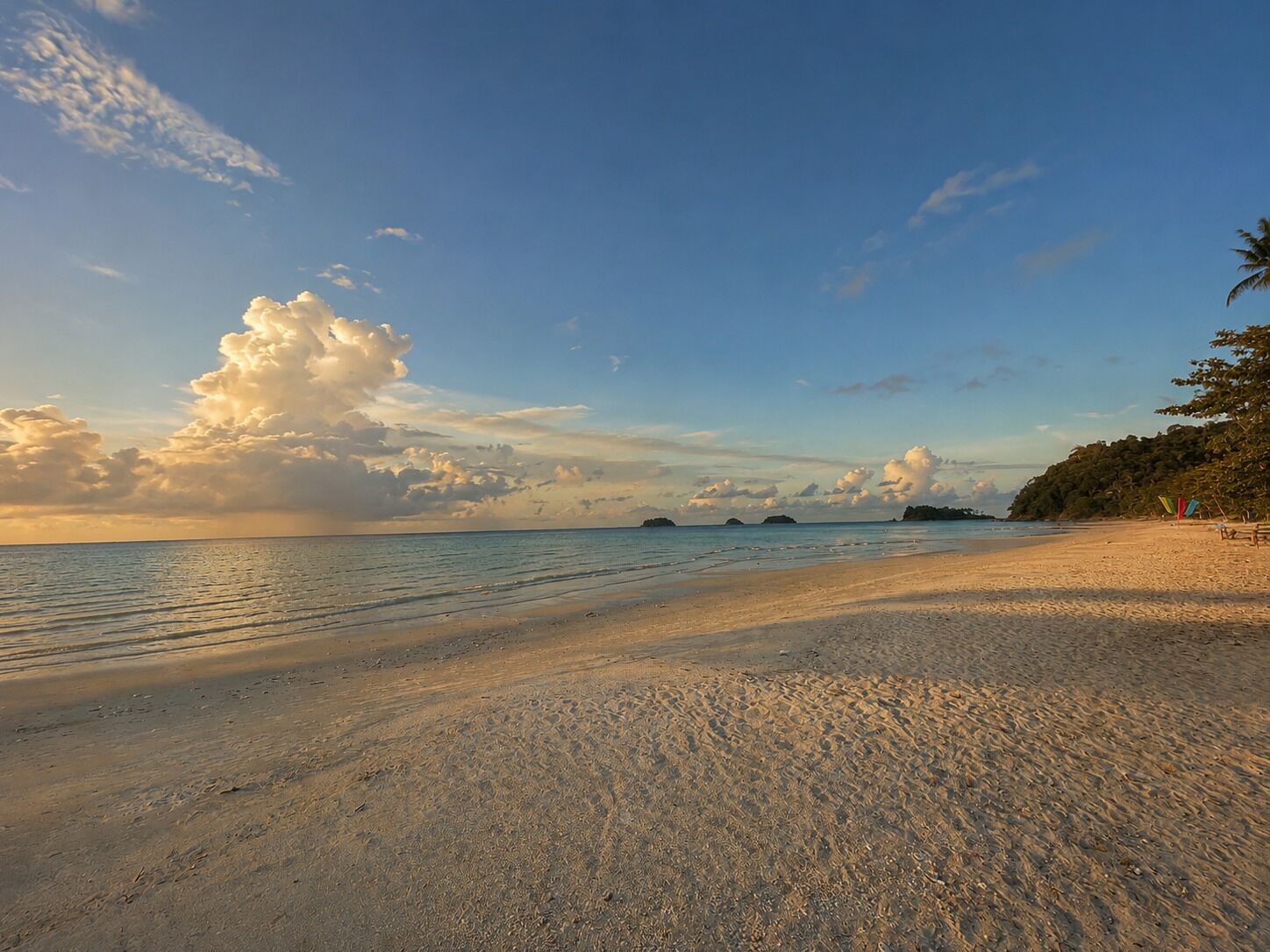 A beach with clear skies, calm waters, and a sandy shore.