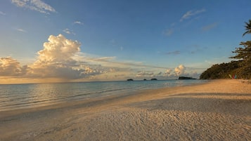 A beach with clear skies, calm waters, and a sandy shore.