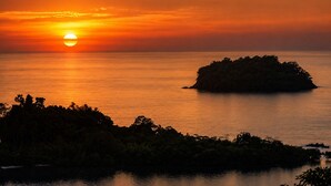 A sunset over a calm sea with a small island in the foreground. - Vanara Bungalows  (Ko Chang)