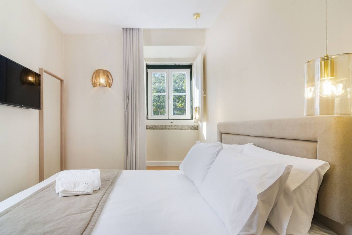 Une chambre d’hôtel avec un lit, une télévision, une fenêtre et une salle de bain visible à travers la porte.