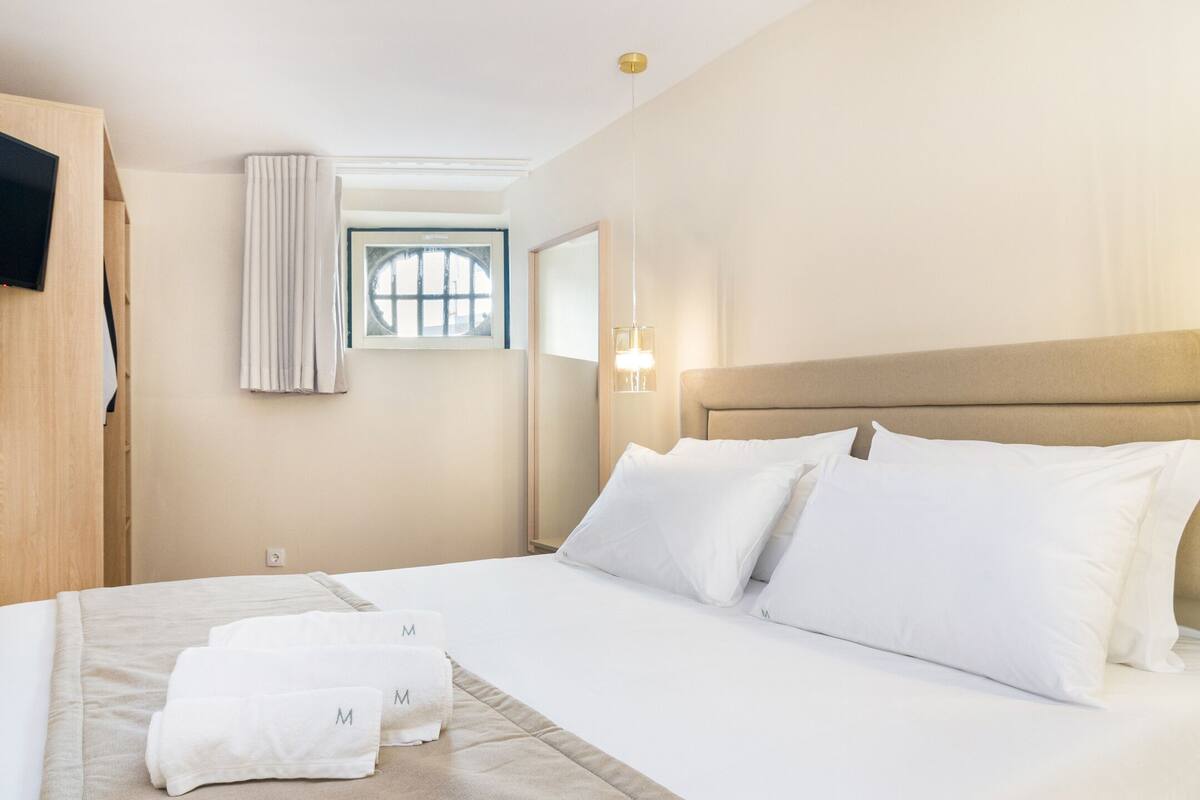 Une chambre d’hôtel avec un lit, une télévision, une fenêtre et une lampe.