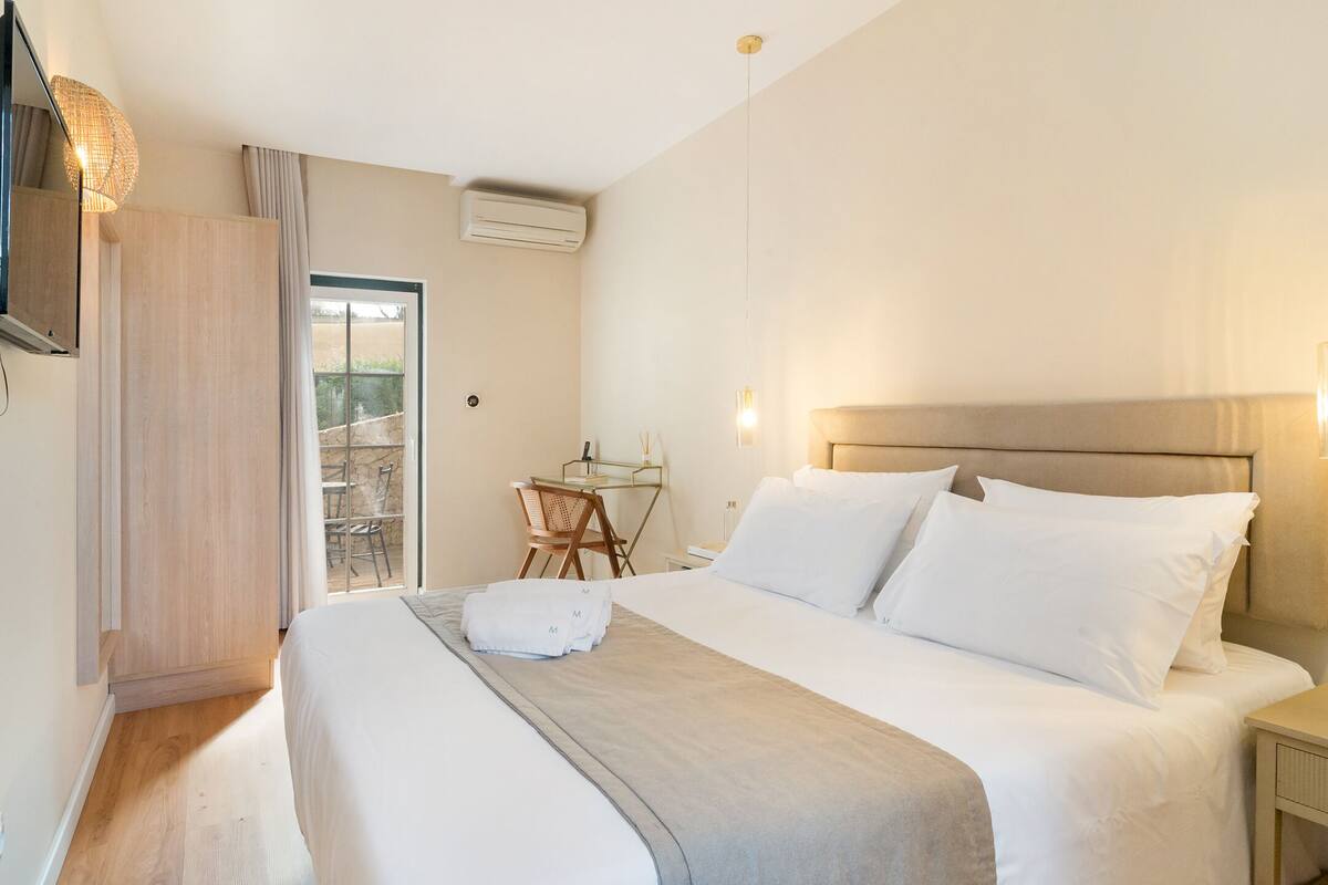 Une chambre d’hôtel avec un grand lit, un bureau avec une chaise, une télévision et un appareil de climatisation.