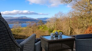 A wicker table with a view of mountains and a lake. - Paddock House (Windermere)