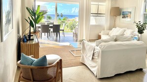 Une chambre d’hôtel avec un balcon, un lit, une chaise, un bureau et un ventilateur de plafond.