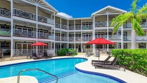 Un hôtel doté d’une piscine, de plusieurs balcons et de parasols rouges.