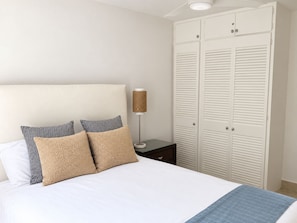 Ein Schlafzimmer mit Bett, Kissen, einer Lampe und einem Kleiderschrank.